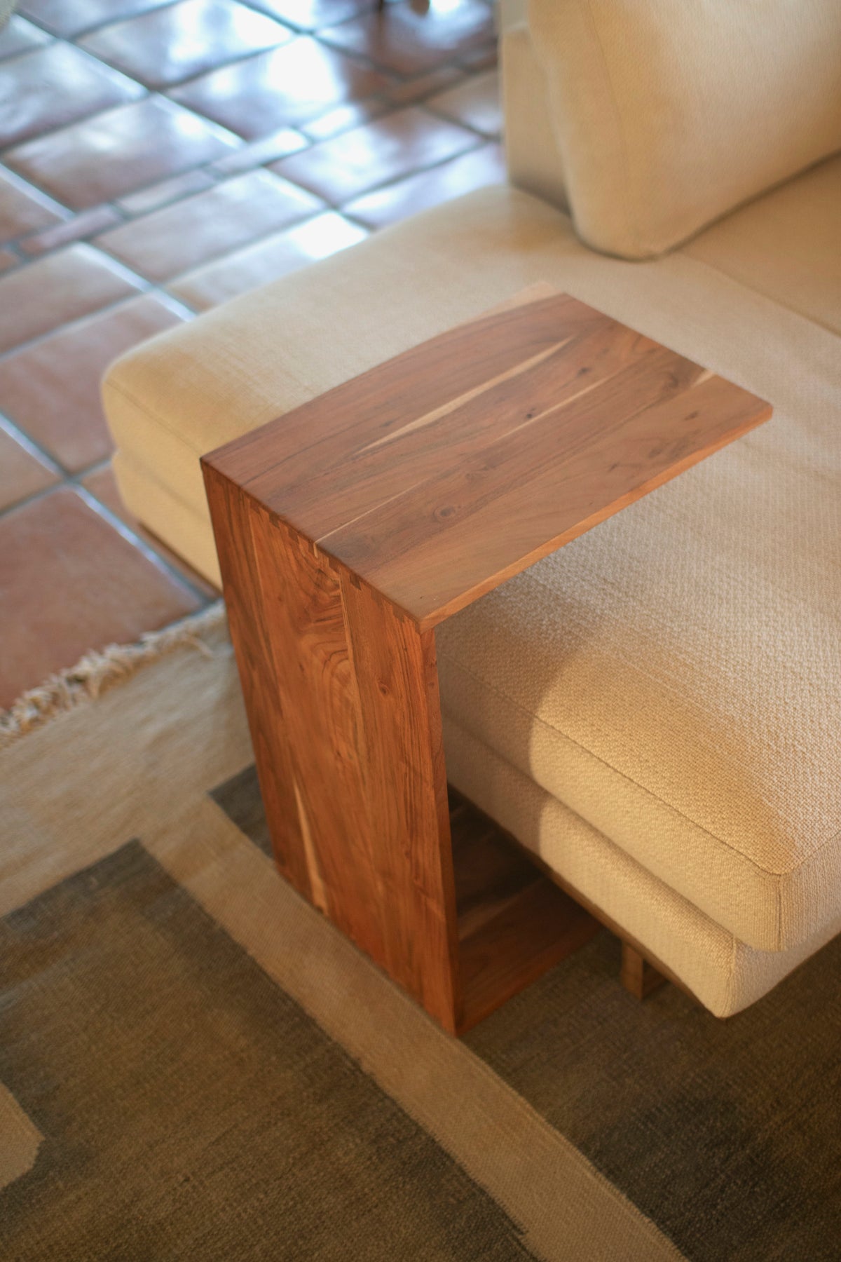Acacia Wood Accent Table beside a light-colored sofa, featuring rustic design and dovetail joints.