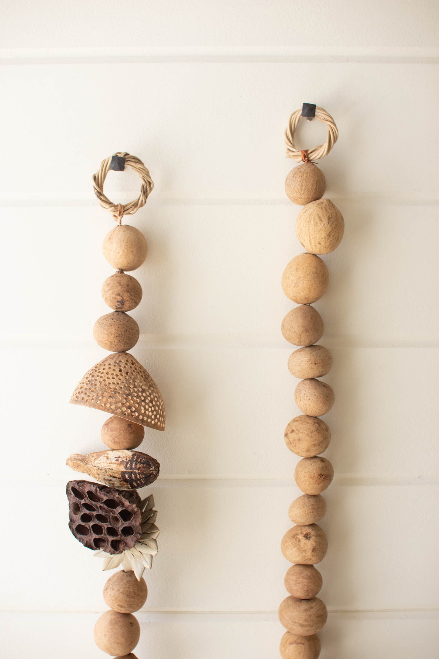 Dried Mixed Botanical Garland with natural wooden beads and dried plant elements hanging on a wall.