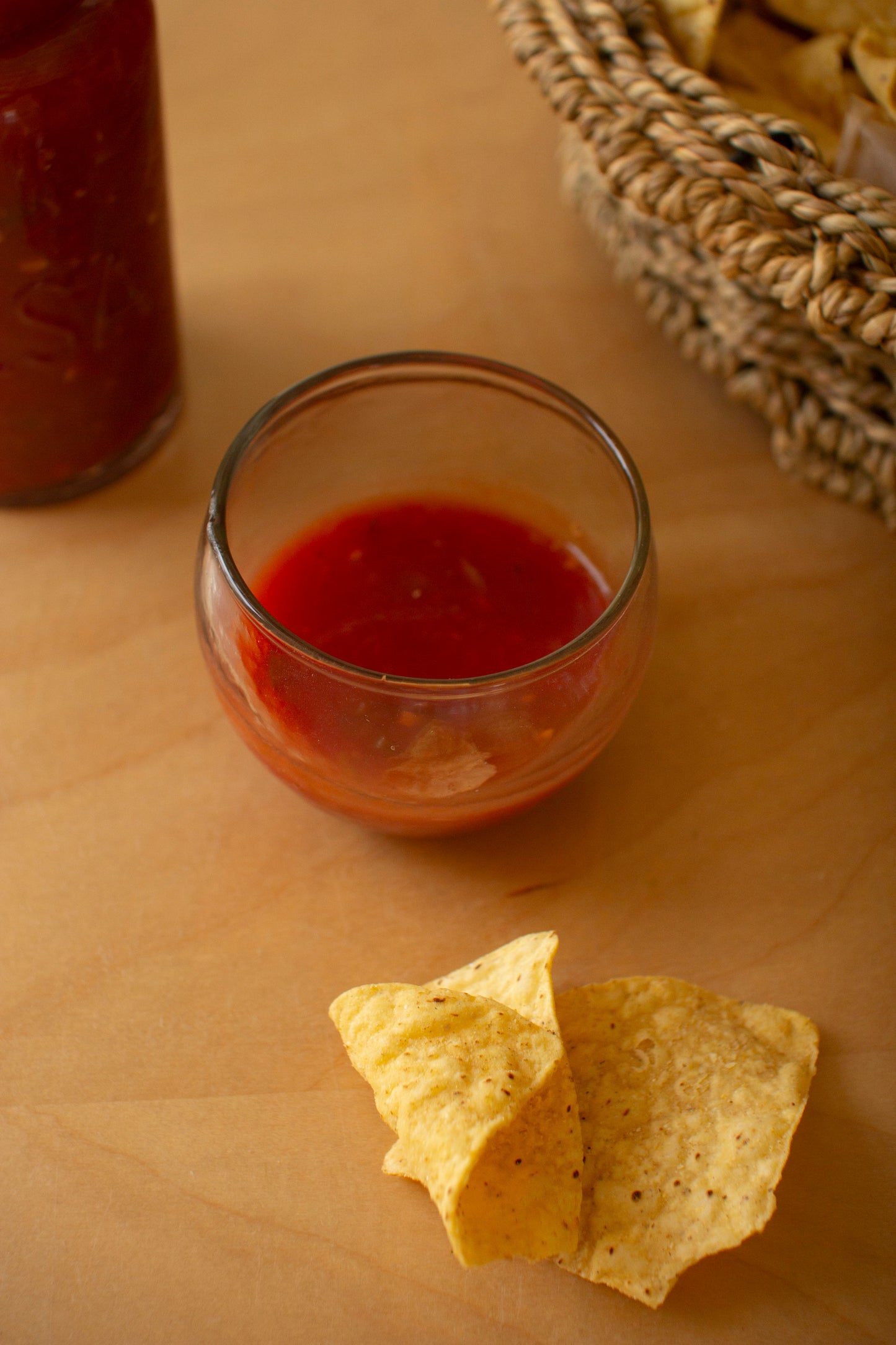 GlassSalsaPitcherwithFourBowls - Glass of red salsa with tortilla chips on a wooden surface