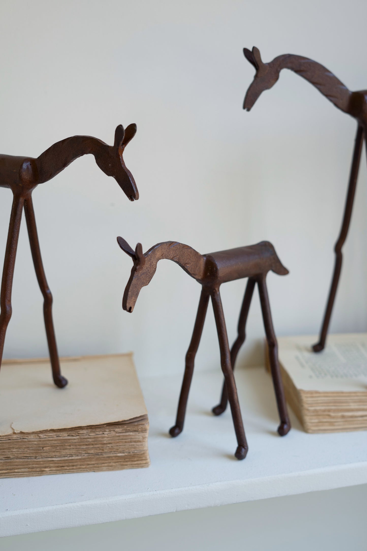 Hand-Forged Iron Horses trio of equine sculptures with distinct sizes displayed on a white shelf.