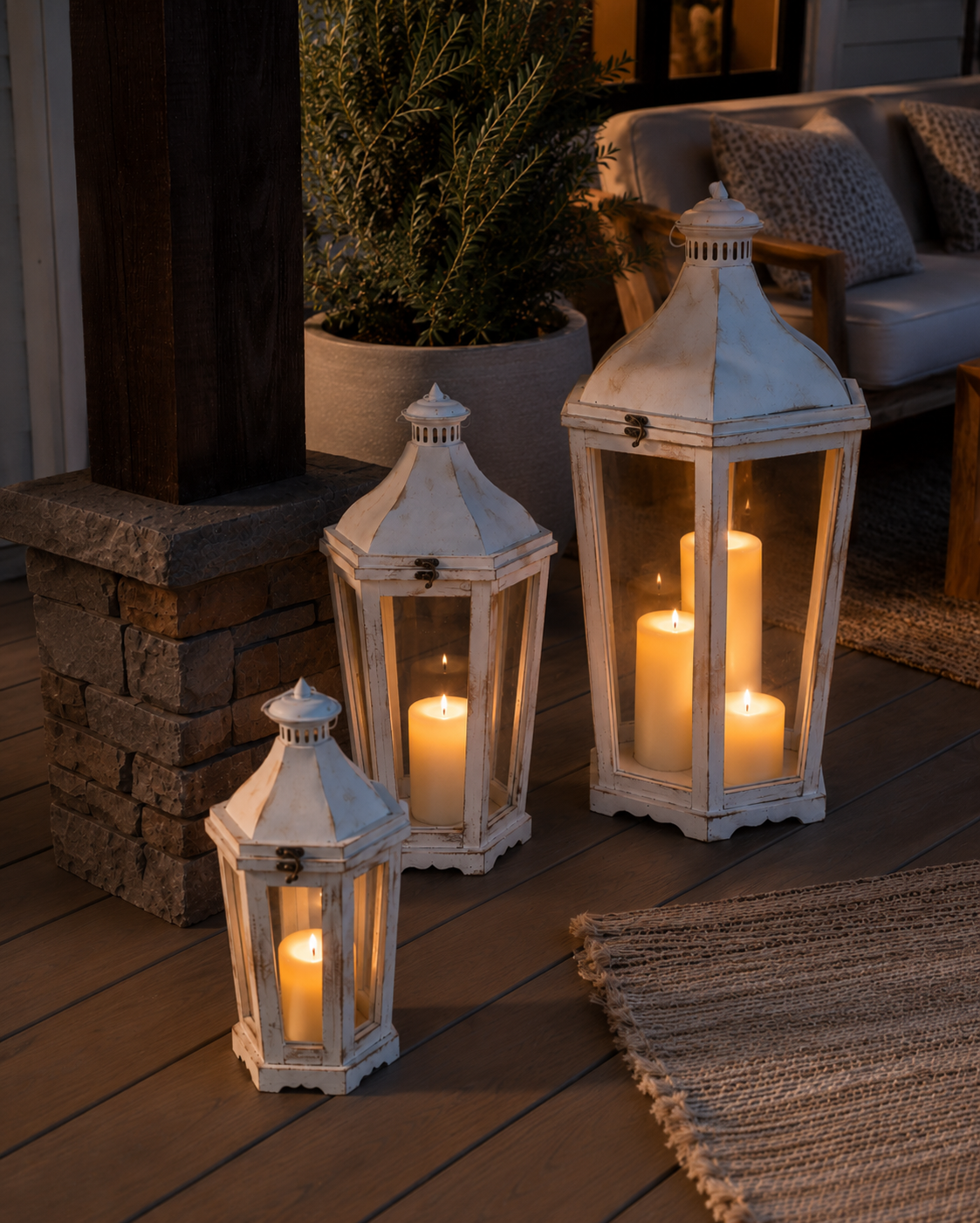 RusticPorchLanterns-setof3-whitedistressed-Set of three white lanterns with candles on a wooden deck.