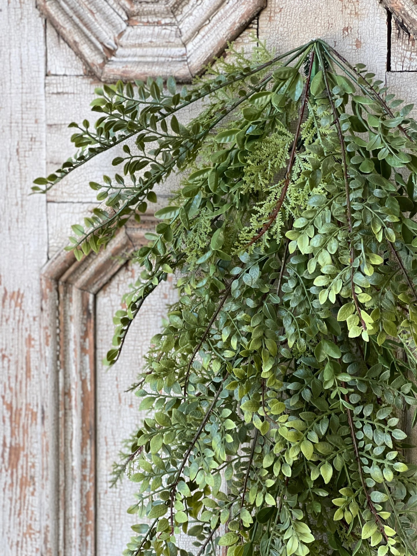 Artificial spring green garland hanging against a wooden wall