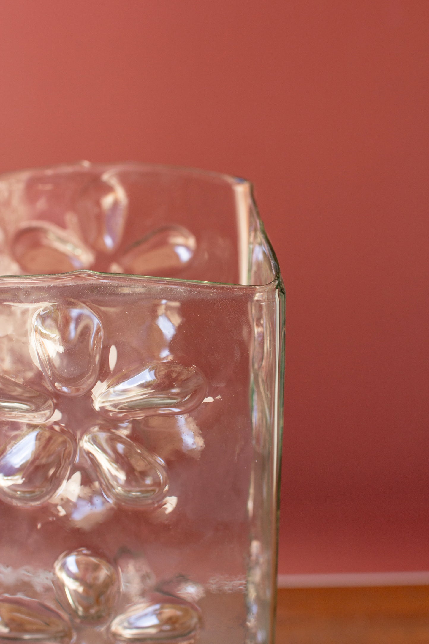 Square Glass Vase with Embossed Flowers showing 3D floral details against a softly colored background.