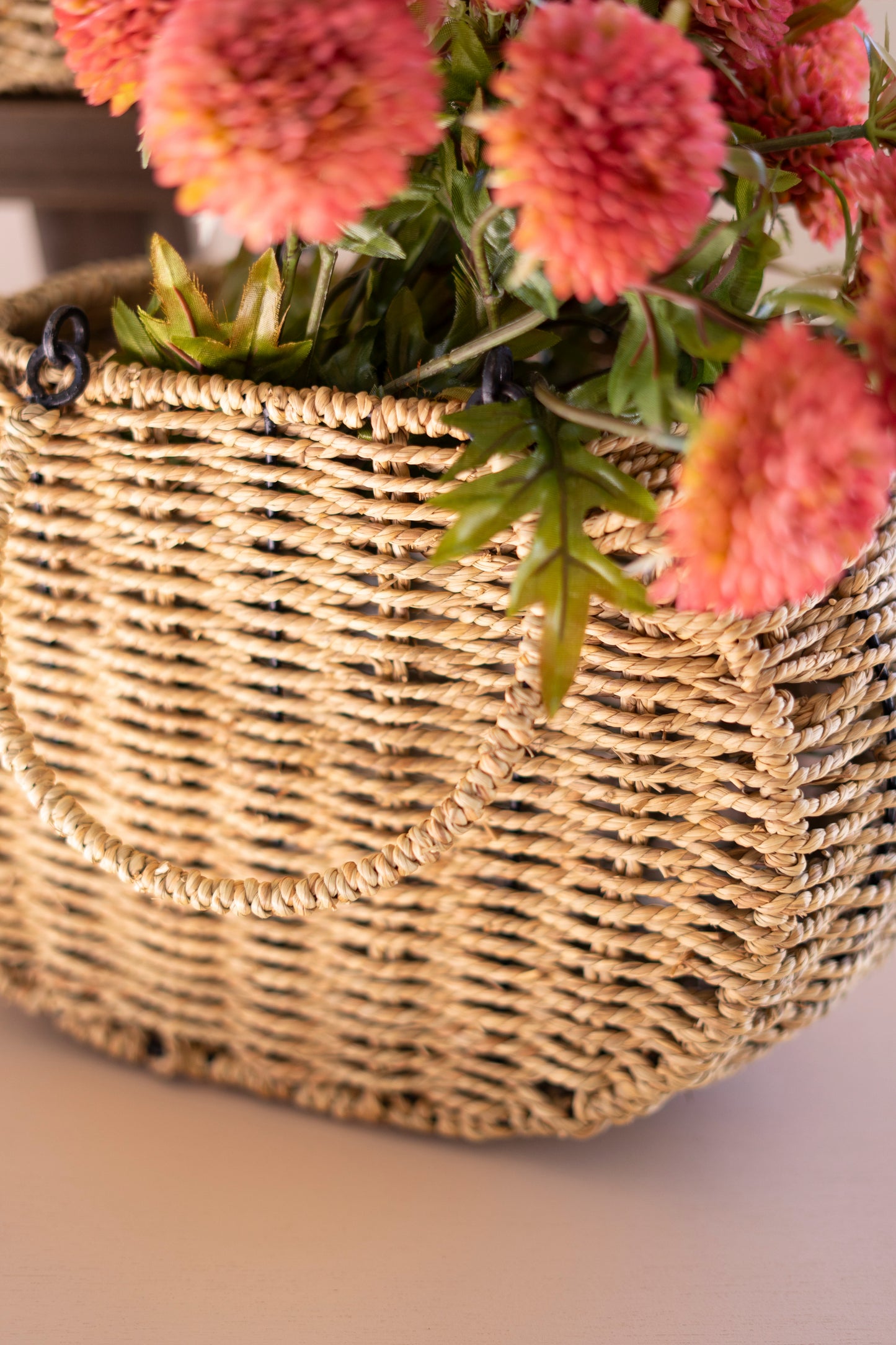 Woven Vine Baskets with Hinged Handles- Set of 2 featuring a decorative handle and filled with pink flowers.