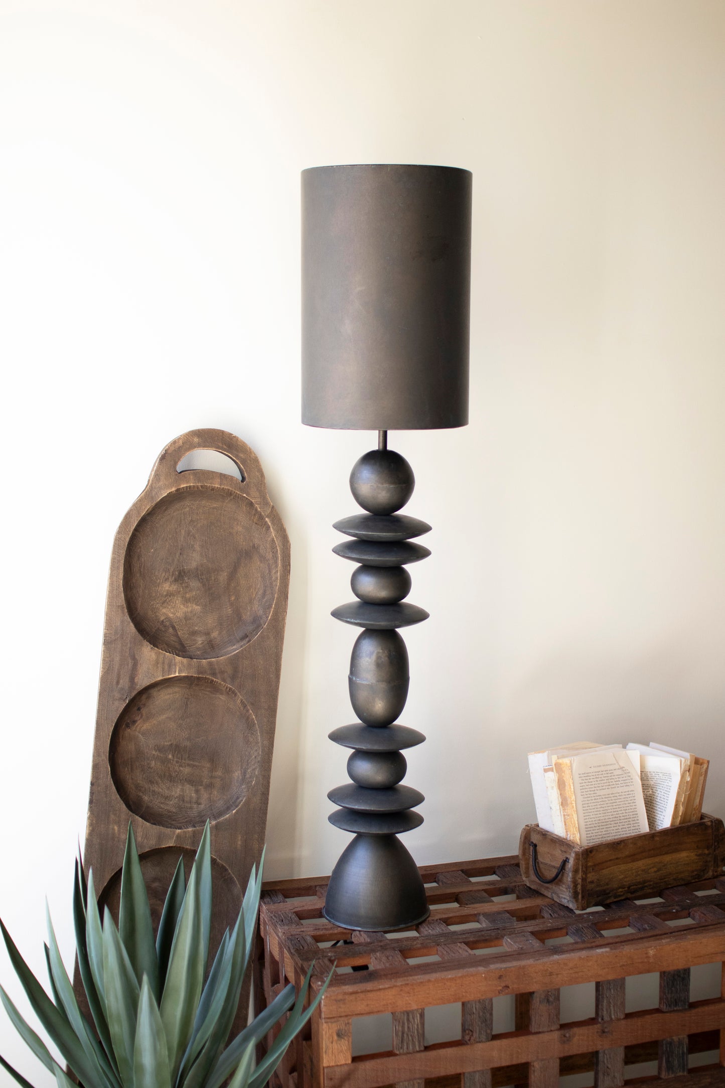 Antique Bronze Table Lamp with sculptural stacked base and simple shade, set on a wooden table with decor.