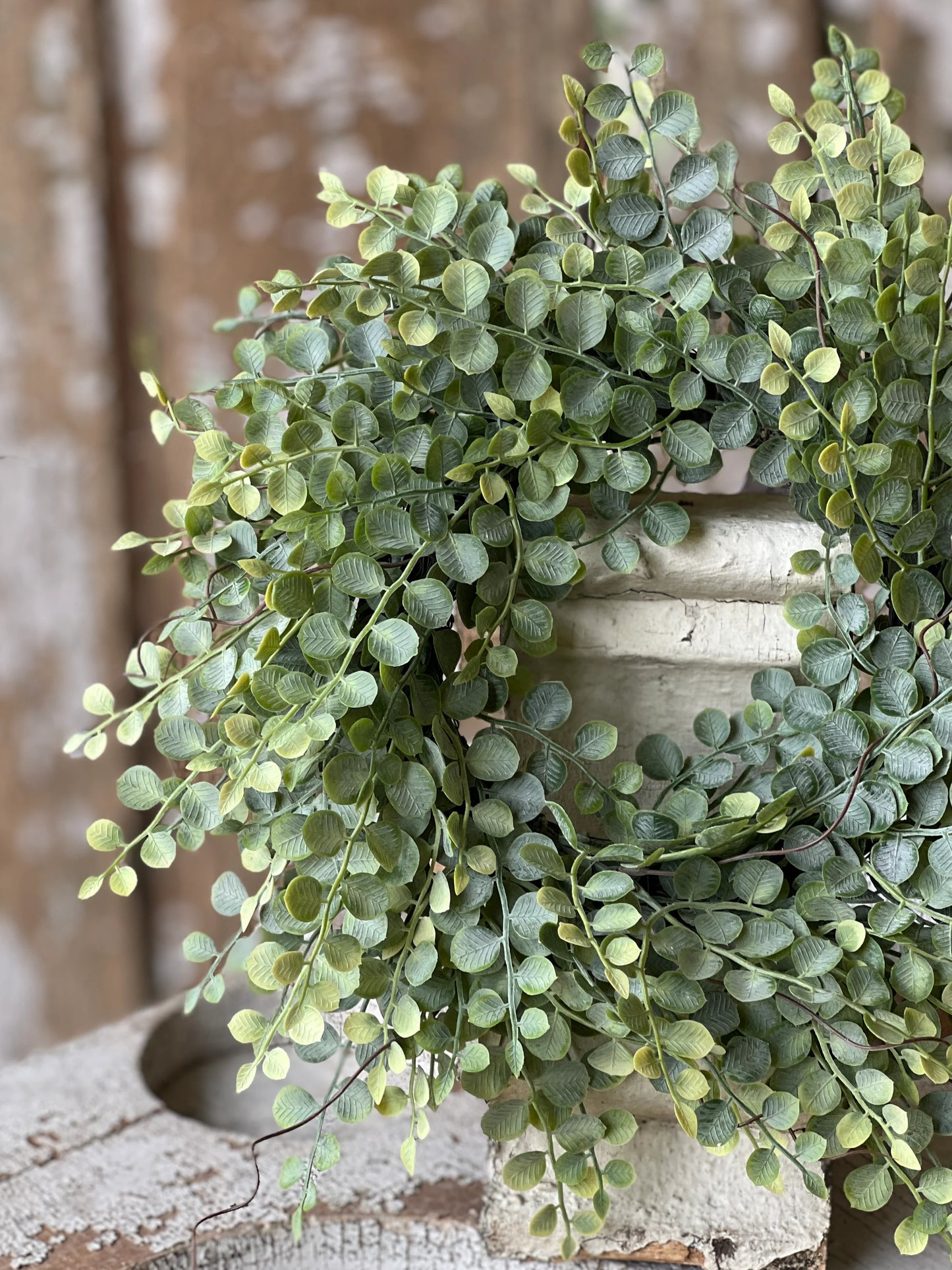 Cherub Vine Candle Ring featuring textured green leaves and tendrils, displayed on a rustic surface with a neutral pot.