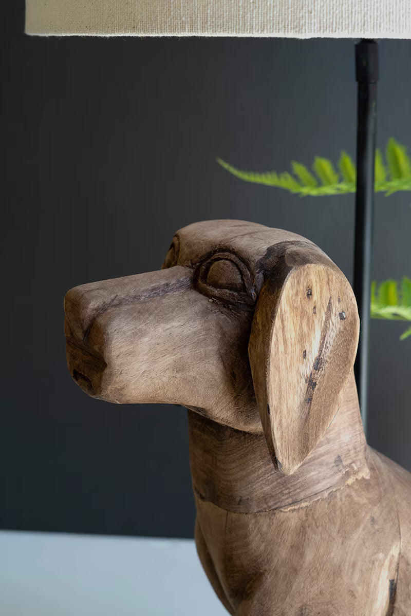 A carved wooden dog head lamp or decorative sculpture shown in close-up, with a beige lampshade and dark background visible.