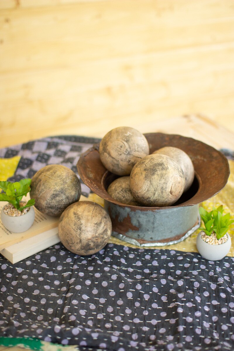 Hand-Carved Mango Wood Spheres in a rustic bowl surrounded by greenery and fabric, showcasing their unique texture.