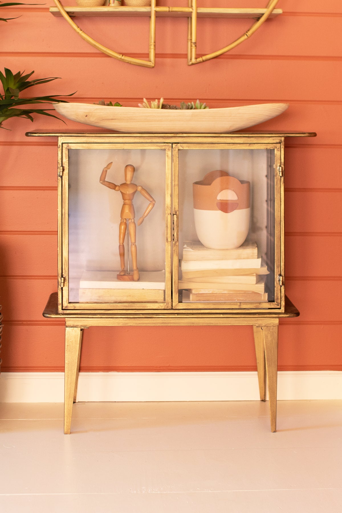 1sandGlassTwo-DoorCabinet with decorative items against a peach-colored wall