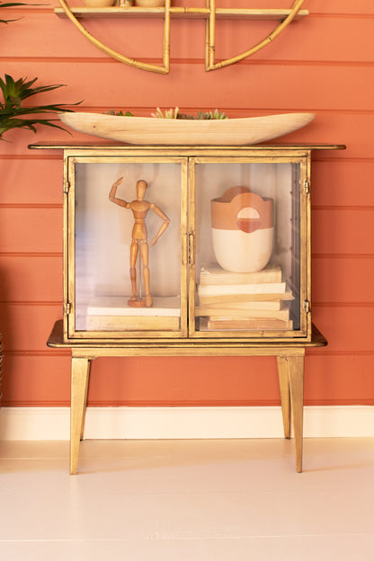 1sandGlassTwo-DoorCabinet with decorative items against a peach-colored wall