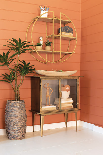 AntiqueBrassandGlassTwo-DoorCabinet and plant against an orange wall.