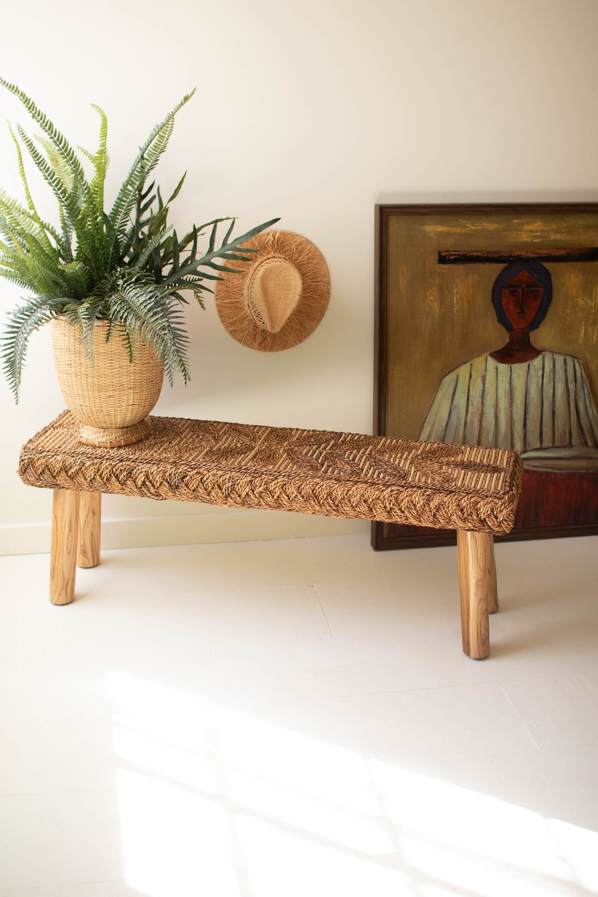 Banana Fiber and Teakwood Bench with hand-woven seat, natural plant, and art piece in background.
