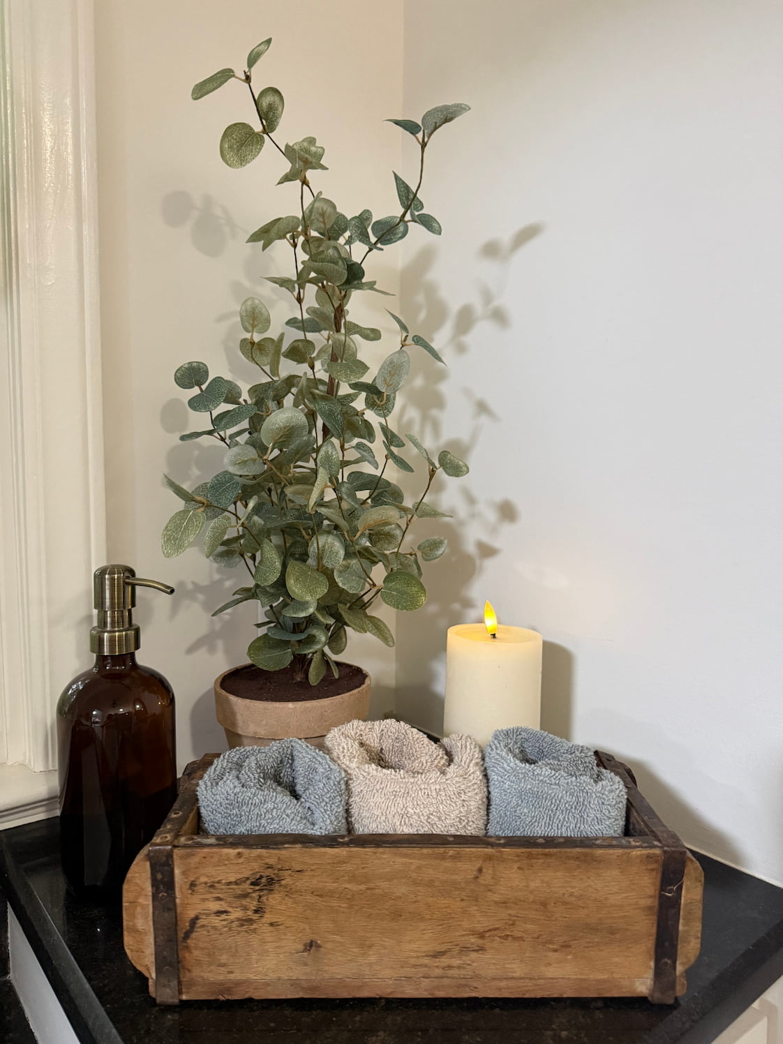 Bathroom decor -cabinet with a plant, candles, and soaps in a wooden brick mold.