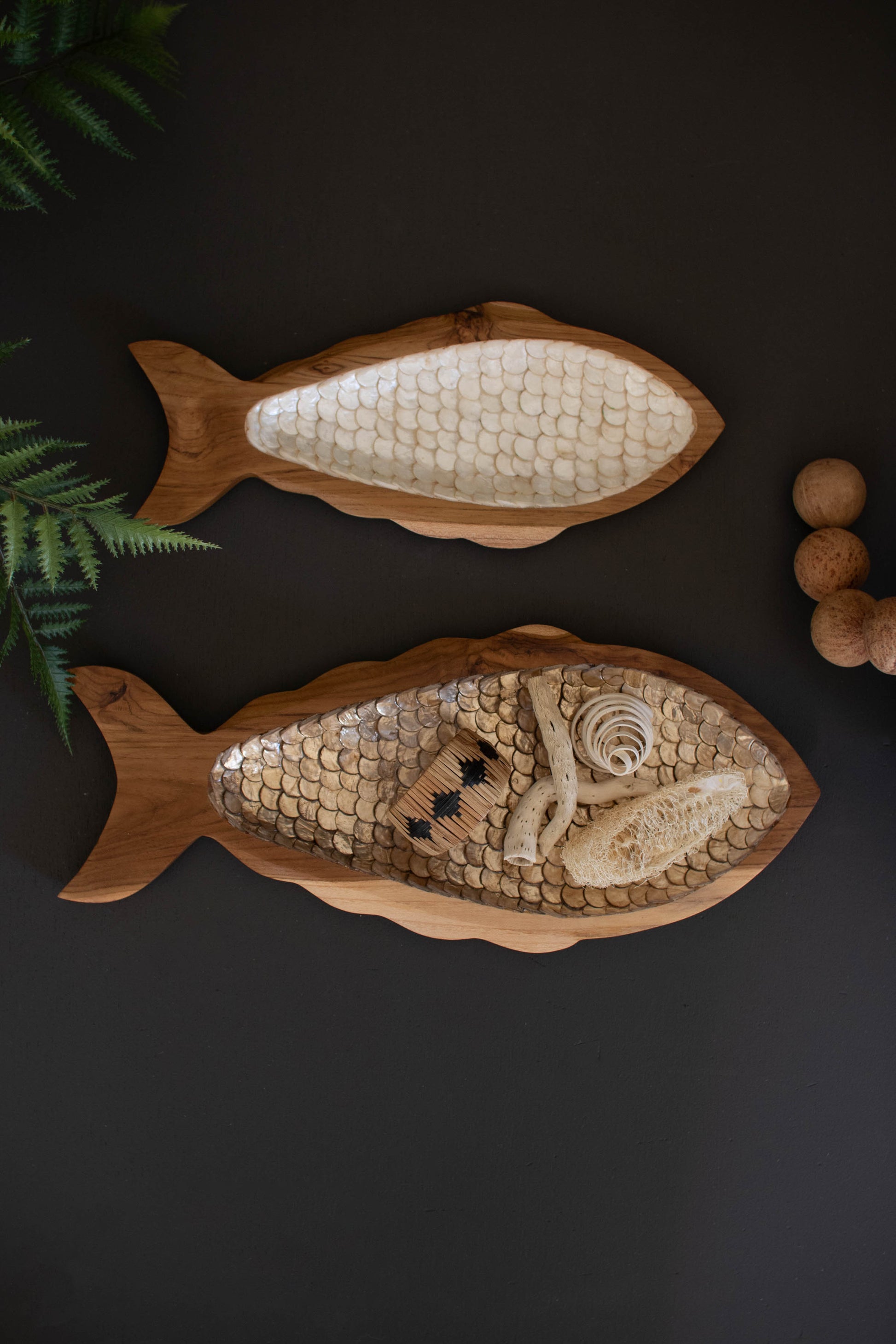 CarvedTeakFishwithCapizDetail-Setof2 - Two wooden fish-shaped trays with decorative patterns on a dark surface.