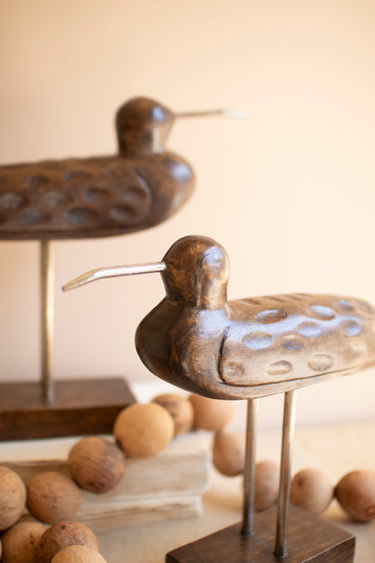 CarvedWoodenShorebirdsonStands-Setof2-9 - Decorative bronze bird sculpture on a stand with wooden beads in the background