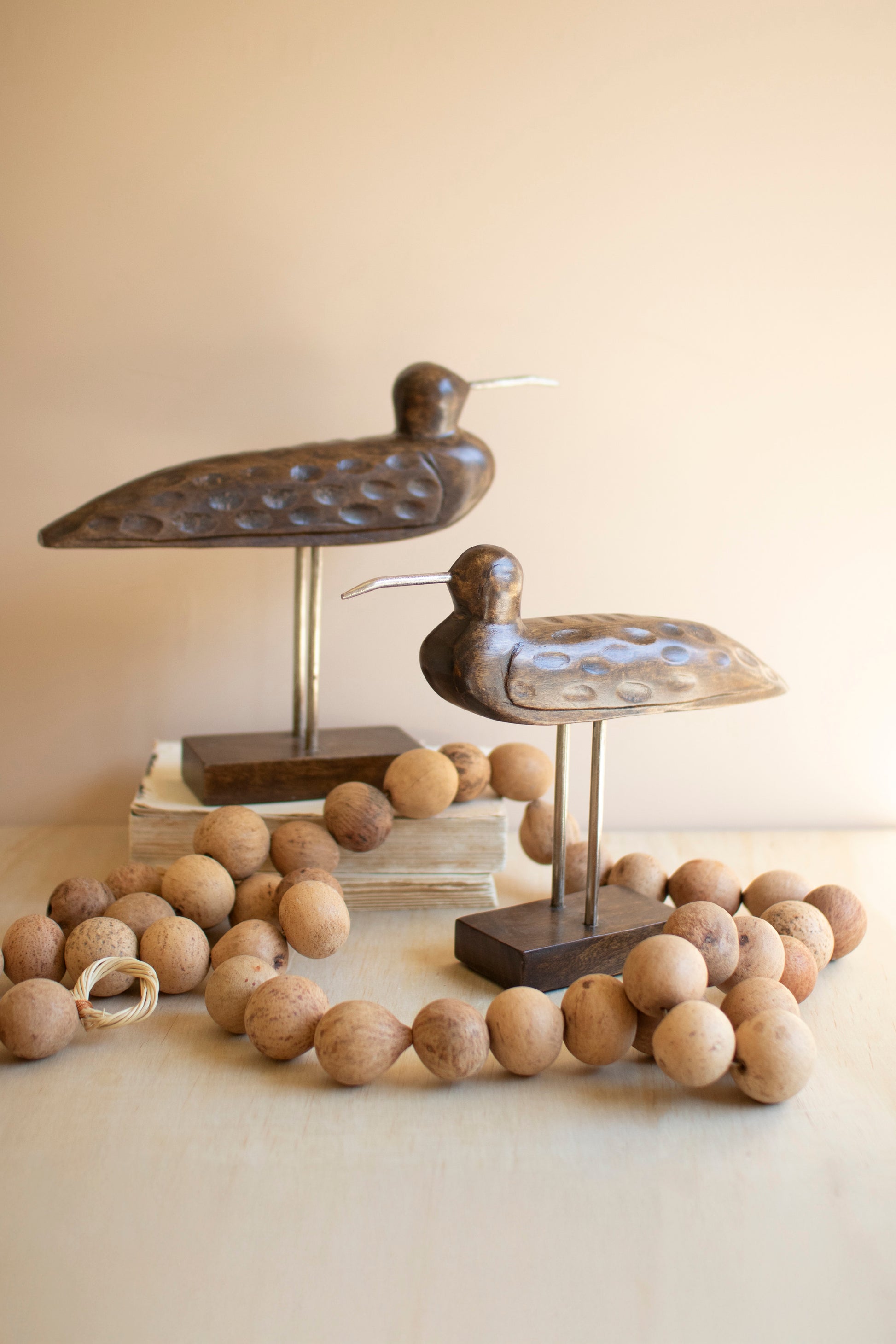 CarvedWoodenShorebirdsonStands-Setof2 - Decorative metal birds on stands with wooden beads on a neutral background