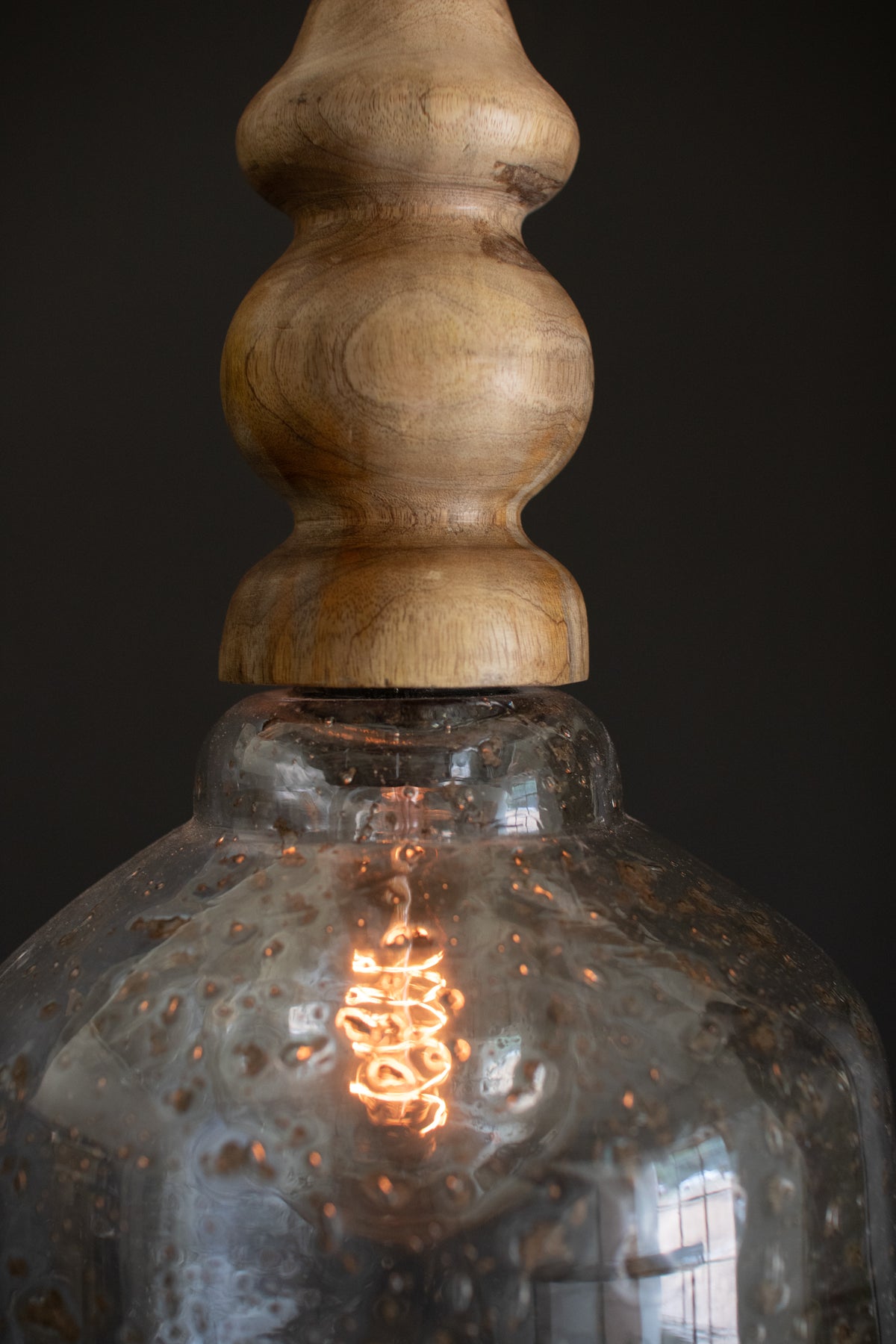 Glass Pendant Light with Wooden Finial featuring a wooden finial and a pebbled glass shade illuminated from within.