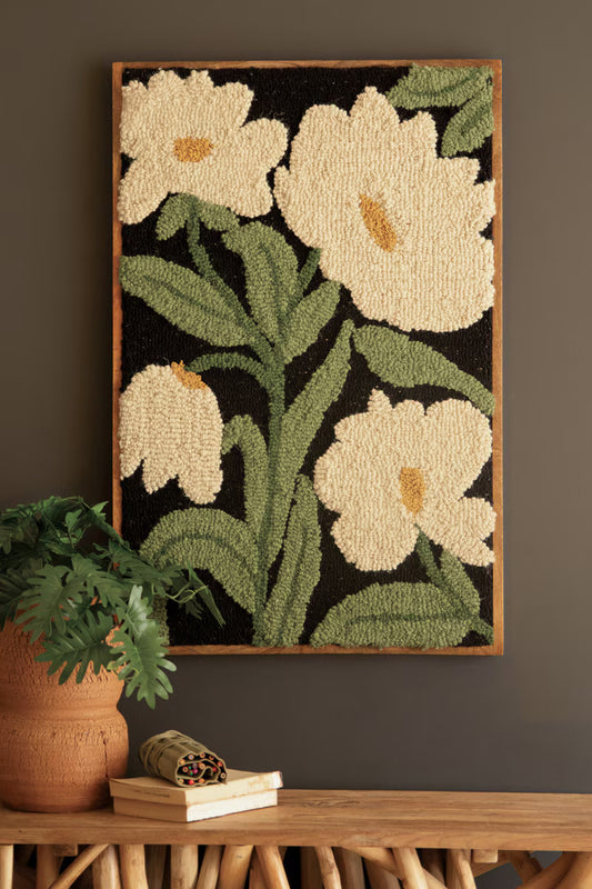 Framed Hand-Hooked Art with White Flowers beside potted plant.