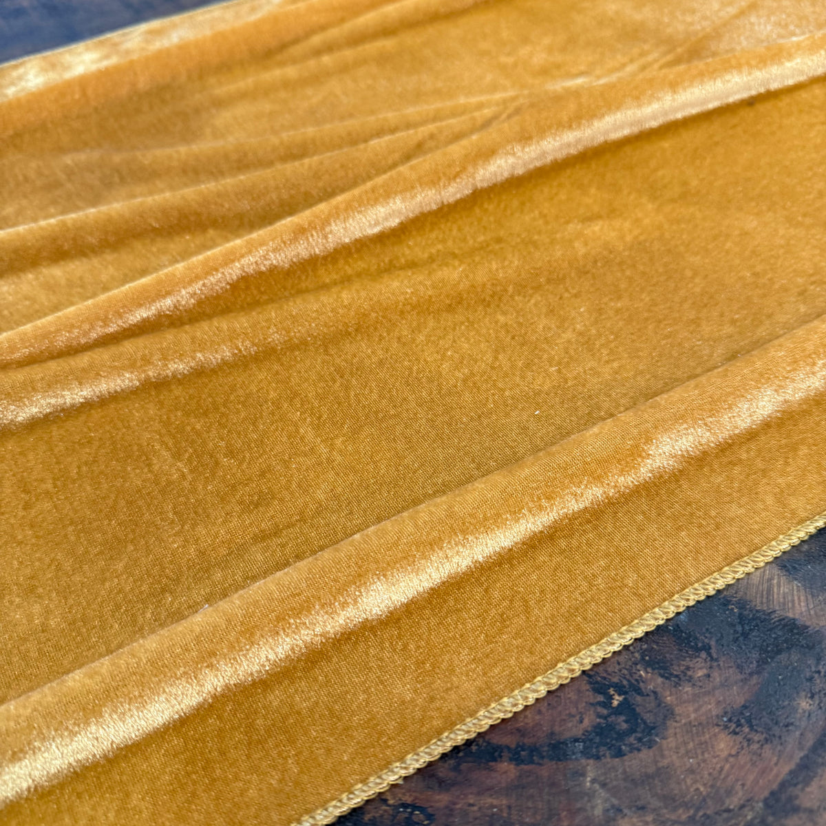A close-up of draped gold table runner for fall