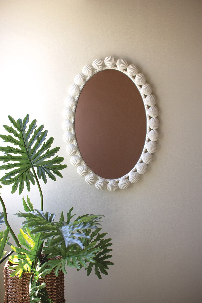 Metal Shell Framed Oval Mirror on a wall next to a plant
