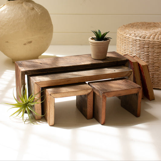 Set of wooden nesting tables with decorative plants on a light background