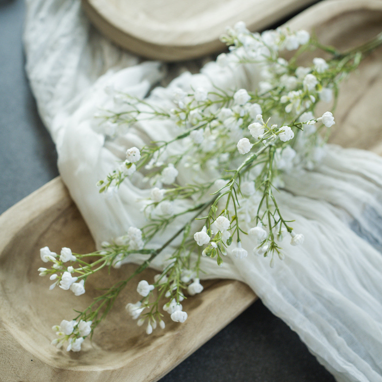 White baby's breath flowers on a wooden surface with a white blanket