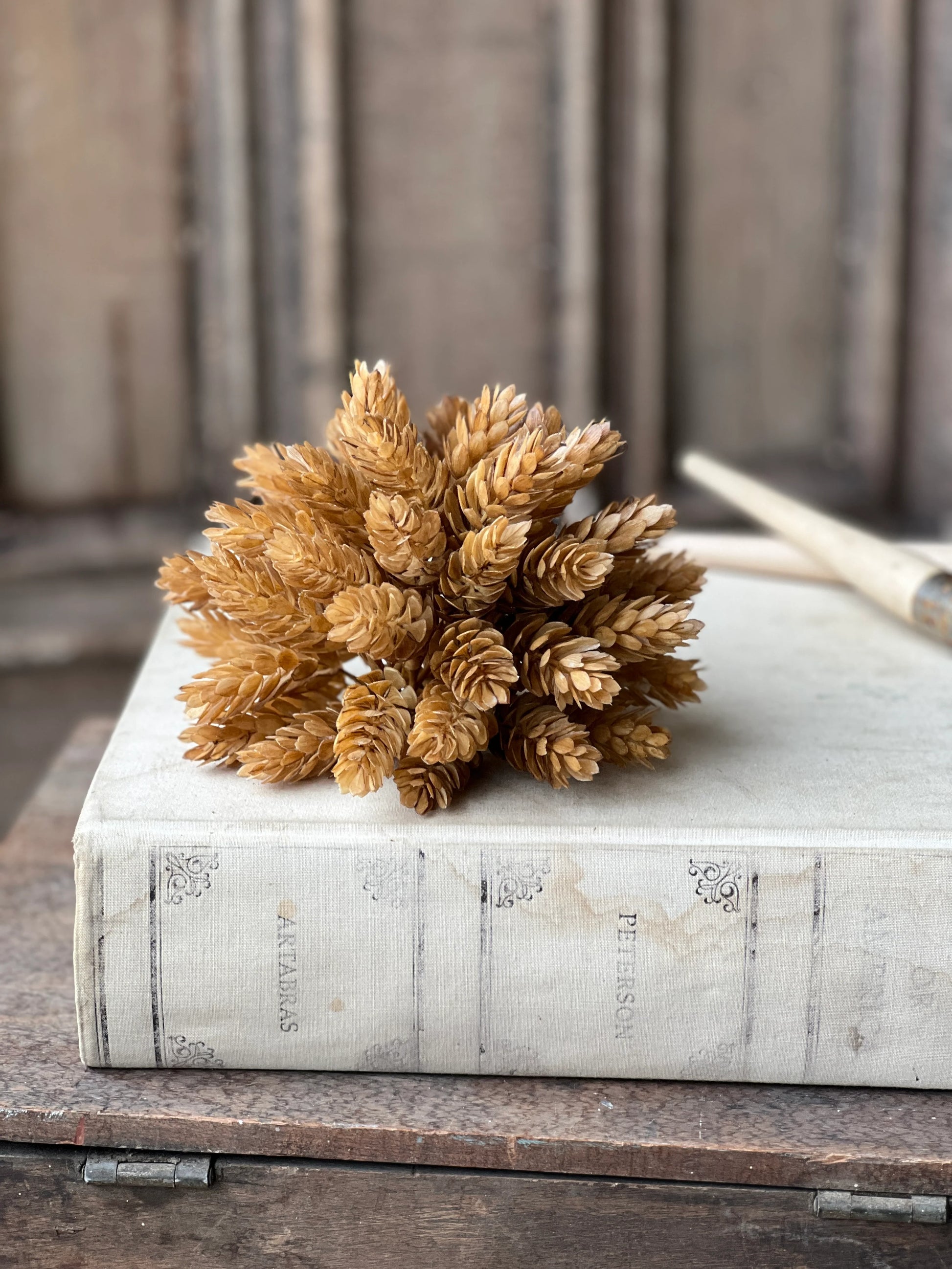 beige fall floral sphere sitting on top of old book styled on wood box