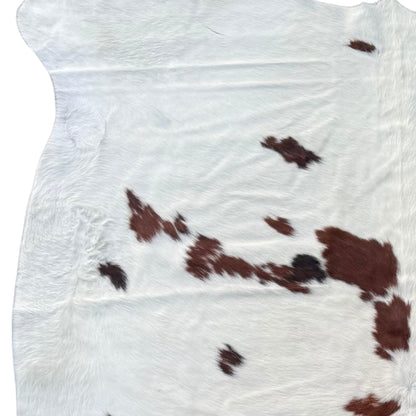 Cowhide rug with brown and black spots on a white background