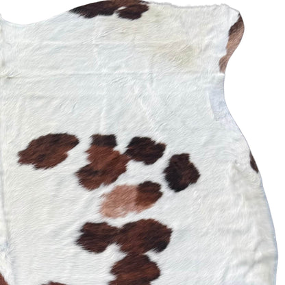 Close-up of a cowhide rug with brown and black patches on a white background
