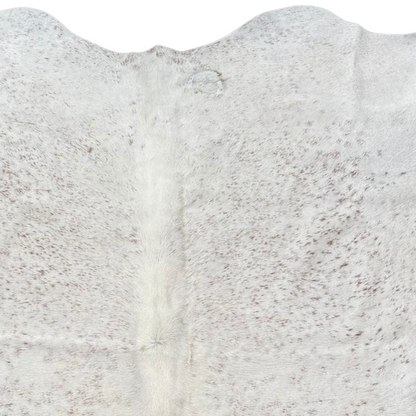 Close-up  white and lightly peppered with brown cowhide rug with G brand