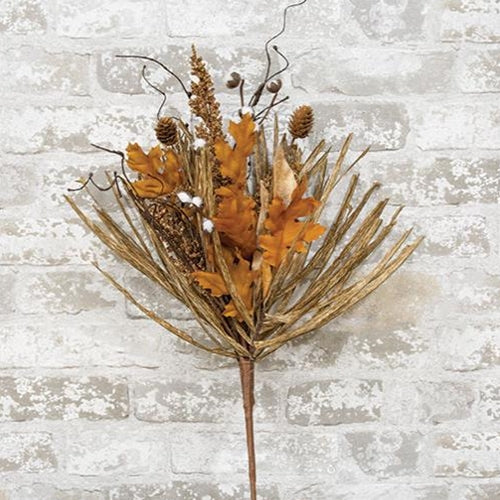 Dried floral arrangement with orange leaves and brown stems against a textured white brick wall.