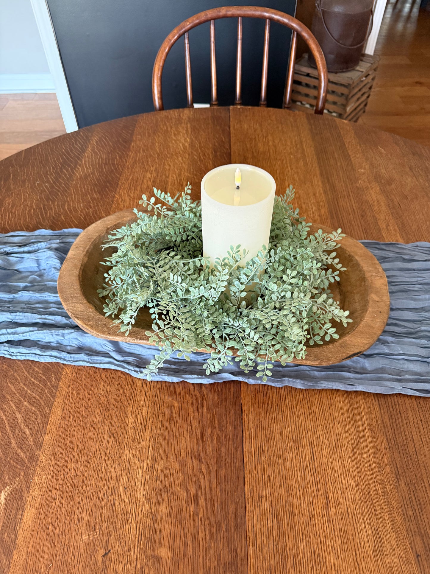 blue table runner and dough bowl with greenery and candle