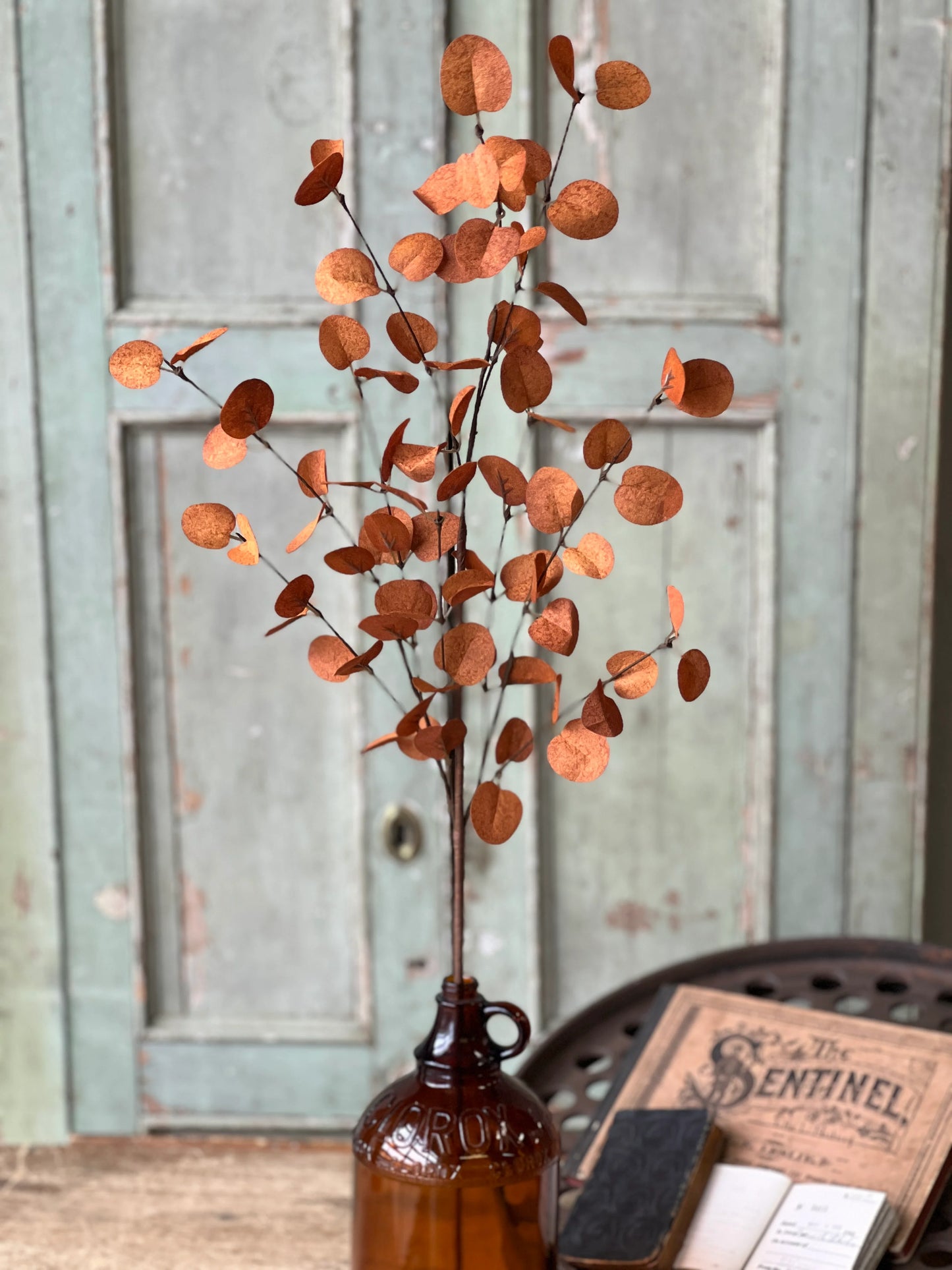 Decorative fall floral orange leaves in a brown bottle against a rustic wooden background