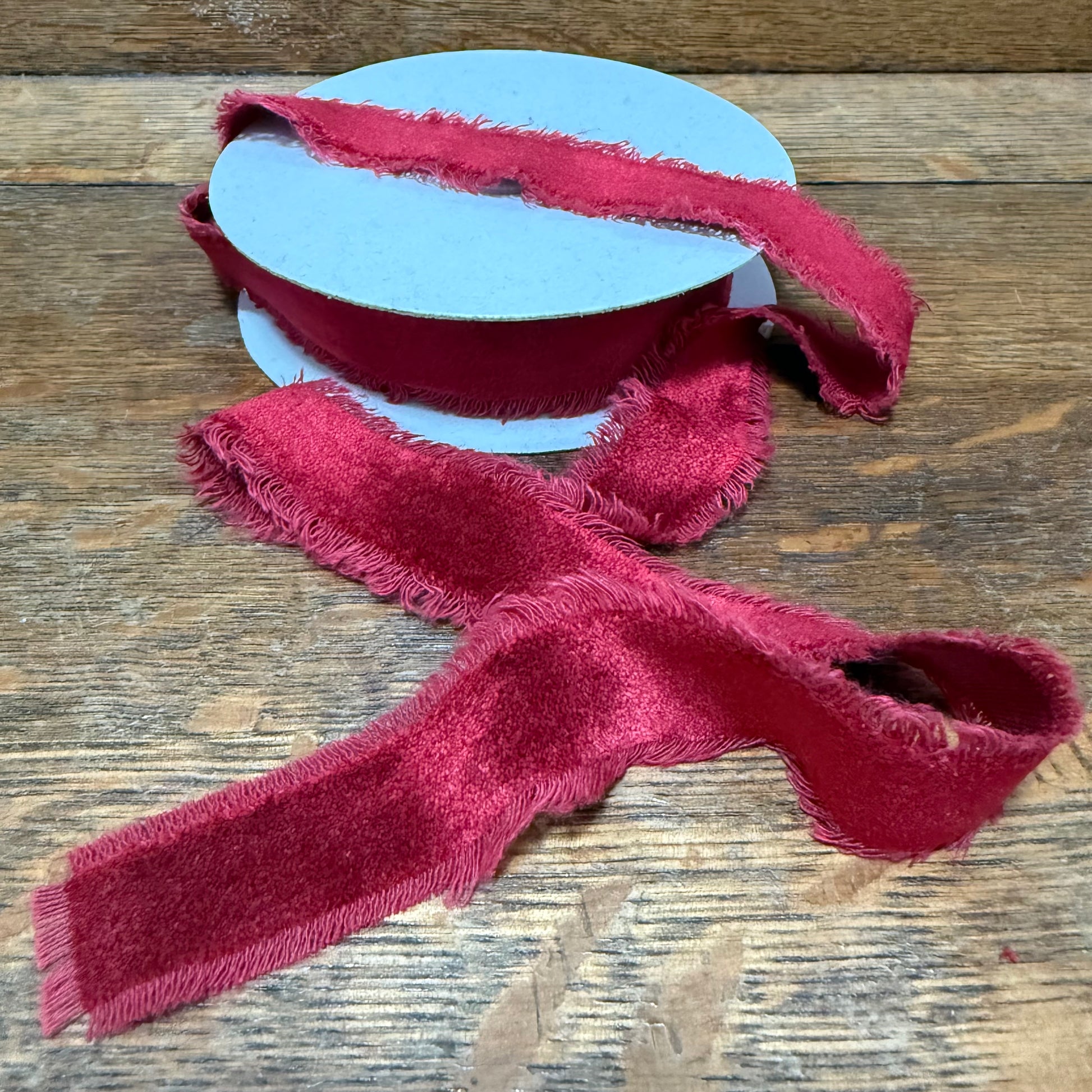 Red textured ribbon on a spool on a wooden surface
