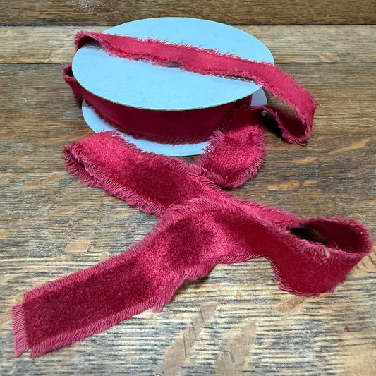 Red textured ribbon on a spool on a wooden surface