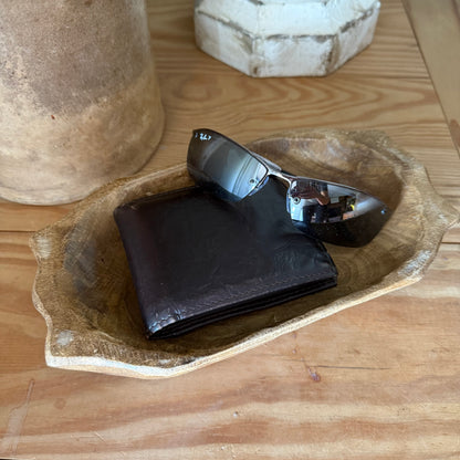 wood bowl holding  wallet and sunglasses on a wooden surface 