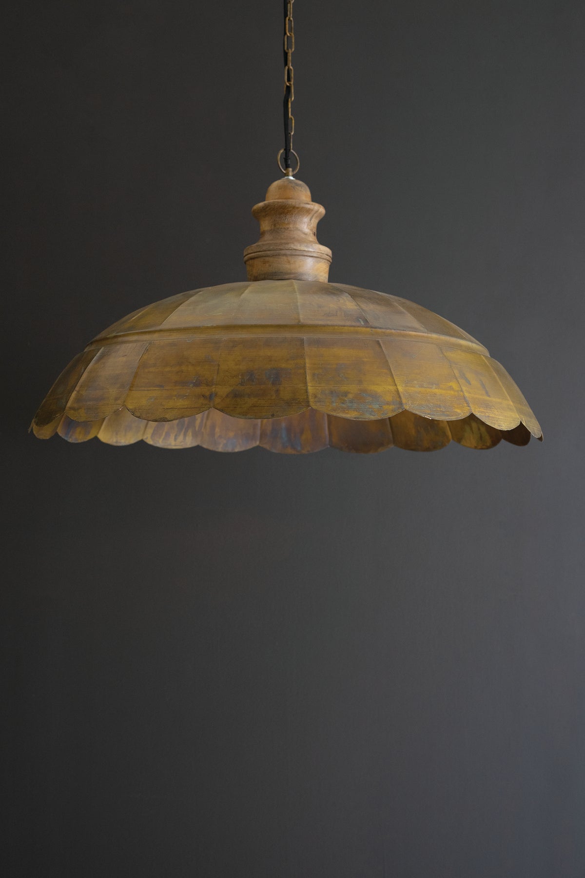 Antique Brass Dome Pendant Light with Wood Detail hanging with a scalloped brass dome and wooden detail against a dark background.