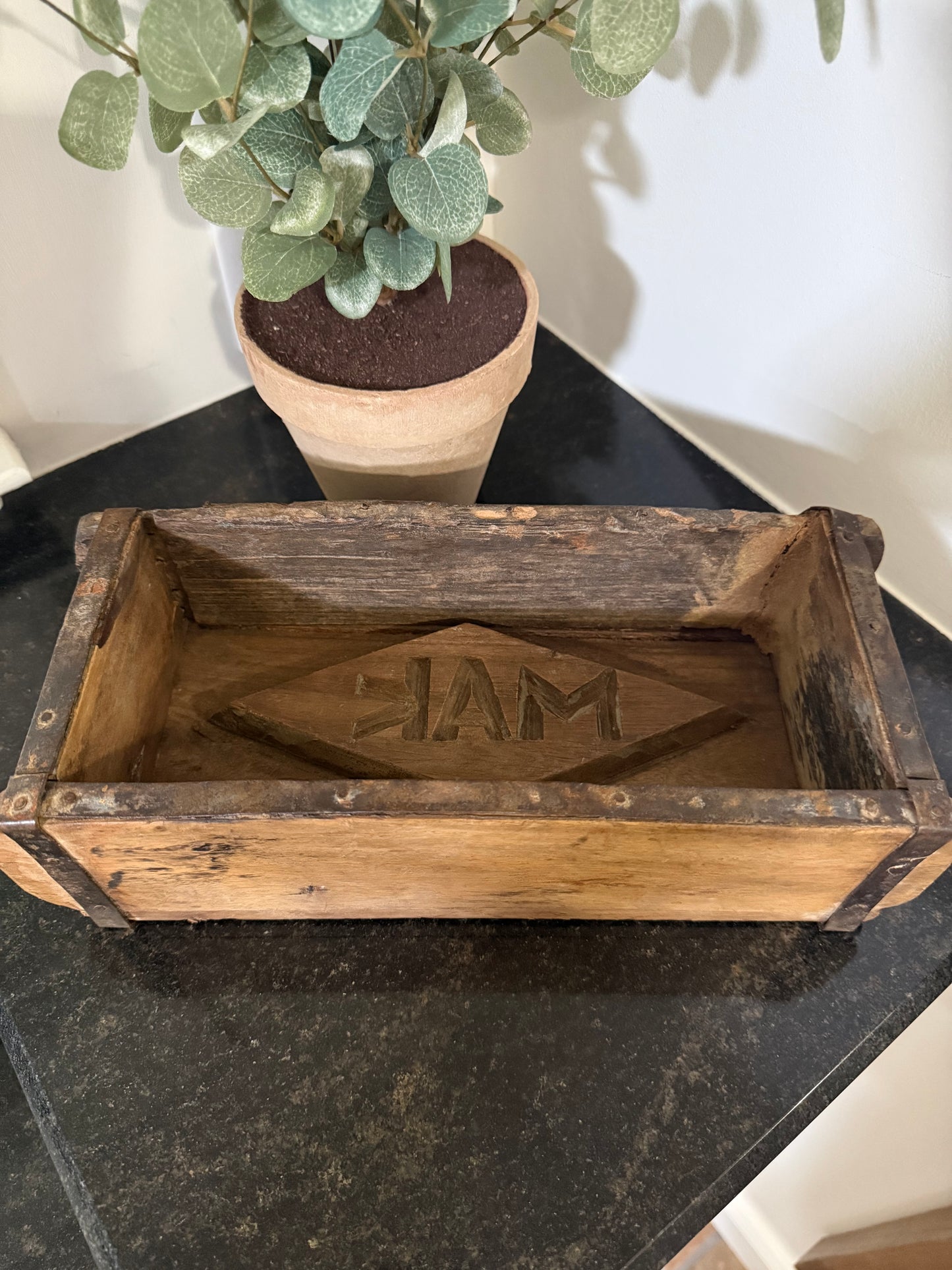 vintage brick mold - antique brick mold with stamp. Wooden box with engraving on a black surface next to a potted plant