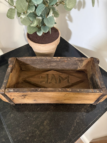 vintage brick mold - antique brick mold with stamp. Wooden box with engraving on a black surface next to a potted plant