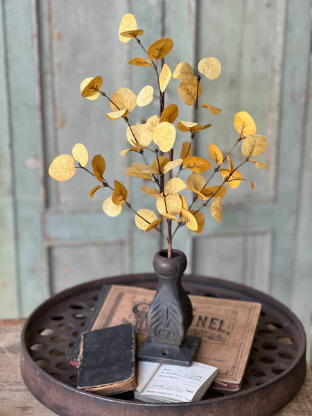 Decorative  fall floral with gold leaves on a round metal tray with vintage books against a wooden background